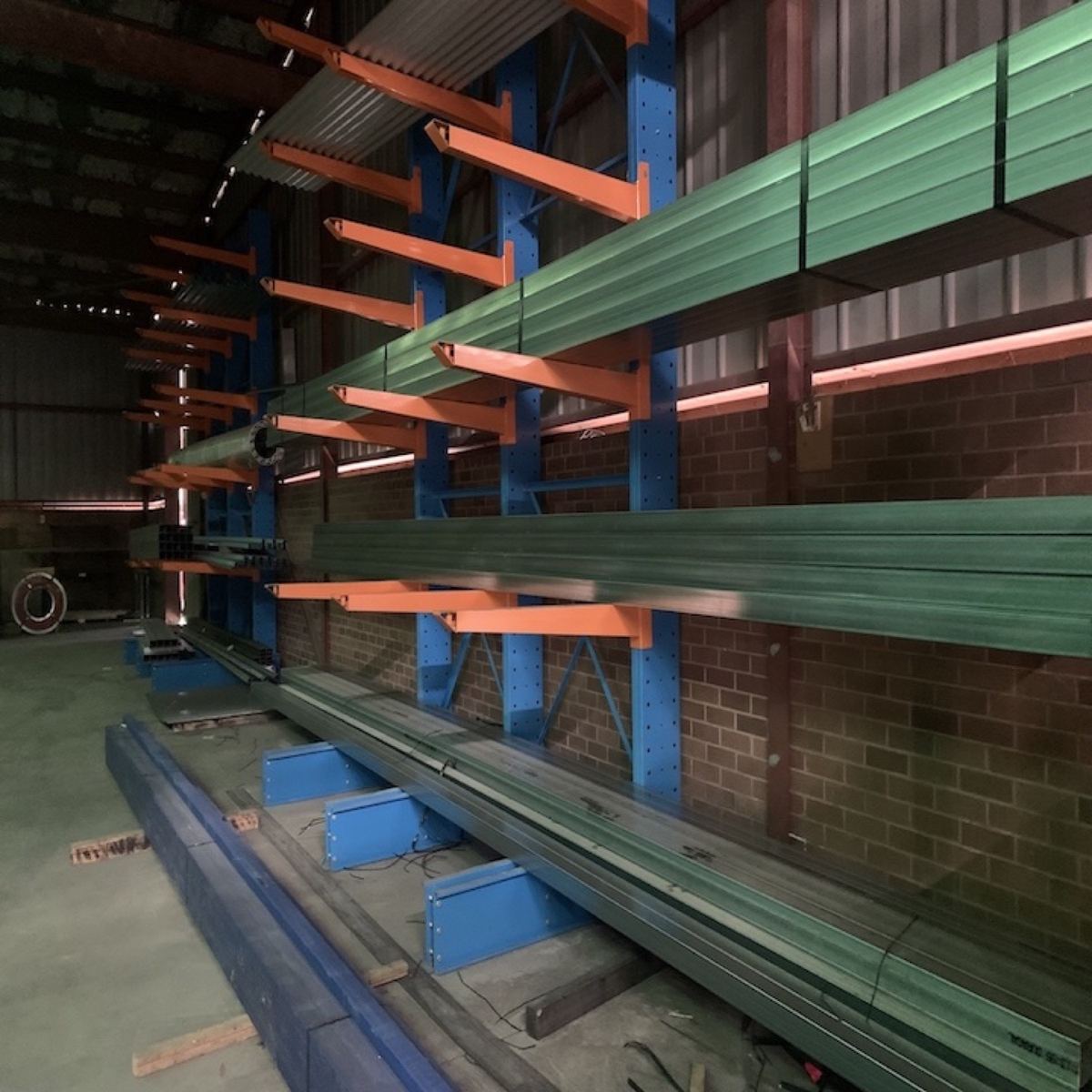 Green primed steel lengths resting on orange rack arms